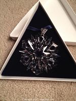 Crystal snowflake ornament displayed in triangular white box lined with blue velvet
