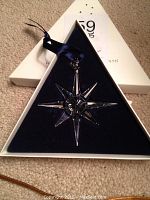 Open triangular box showing clear crystal snowflake ornament with navy ribbon