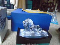 Crystal lion figurine on stand in front of blue box