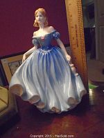 Front angled view of the Melissa figurine showing blue ballgown, orange hair, and rose detail on bodice, with ruler for scale.