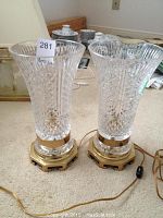 Two matching crystal lamps on carpeted floor, full view of bodies and bases