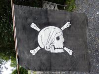 Full flag displayed hanging outdoors, showing the full skull and crossbones design.