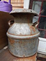 Front and side view of the antique metal cream can showing rust and wear with embossed text faintly visible.