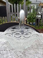 Front and side angled view of clear glass brides basket showing bullseye pattern design and arched handle.