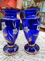 Pair of cobalt blue glass vases with hand painted white flowers and gold trim, shown upright side-by-side.