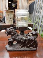 Side angle showing the horse and chariot detail of the spelter cast base and the ribbed clear glass shade mounted on top.