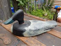 Hand painted early wood carved duck decoy shown from side angle with view of the head and body paint condition.