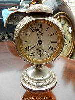 Front angled view of the Junghans alarm clock showing the face, twin bells, and metal base with decorative trim.