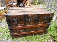Front view of closed trunk showing wood slats, metal bands, central latch and two side latches