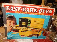 Front of the original Easy Bake Oven box showing the toy oven and a child using it.