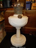 Front view of the white opaque lamp base with metal burner and wick knob visible on top.