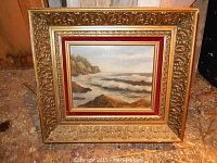 Full view of the original framed oil painting showing ocean scene with waves crashing on rocky shore and ornate frame.