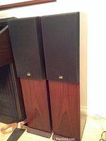 Two tower speakers side by side with grilles installed showing wood veneer cabinets