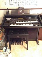 Front view of Technics SX-GX7 organ console with bench and foot pedalboard