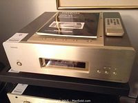 Front view of silver Denon CD player with manual and remote on top