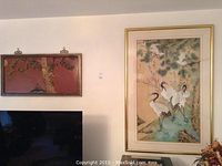 Wide photo showing both artworks hanging on a wall above TV, illustrating size and display context.