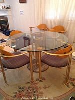 Front view of entire dining set with round glass table and four chairs on floral rug
