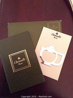 Christofle branded booklets and cutout monogram tool on wood surface