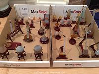 Two tray boxes displaying assorted miniature stone Chinese musical instruments on wood stands