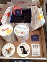 Two decorated cylindrical Lovlots packaging tubes, two white lids with two crystal figurines displayed, certificate booklet and MaxSold card visible