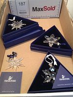 Four snowflake ornaments displayed in triangular boxes with certificate booklet, one loose ornament