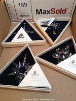 Four Swarovski ornaments in original triangular boxes placed together.