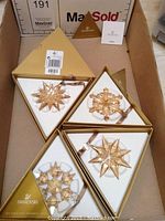 Four triangular gold boxes each containing one gold-tone crystal snowflake ornament