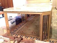 Close-up of square marble top brass end table showing the marble and brass frame.