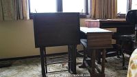 Photo showing four small wooden tables of different sizes and styles, including two TV trays and a small desk, positioned side by side in front of a window
