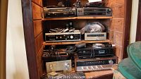 Shelf showing multiple vintage electronic devices including stereo receivers, amplifiers, and a CD player.