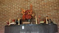 Wide view of entire mantel with all items including train cars, flowers, candles and gargoyle