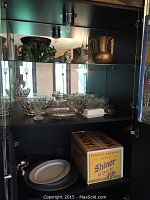 Glass cups, clear glassware including bowls, plates, and shot glasses inside cabinet.