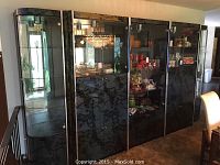 Wide view of the large black china cabinet with five sections, glass front doors with metal trim, marbled finish, some display items inside.