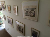 Wall of framed Egyptian style art prints and paintings in various sizes hung on a beige wall.