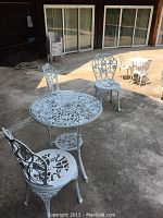 Foreground round table and single chair with ornate openwork on patio