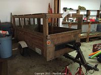 Front corner view showing wooden cargo box, metal frame, wire mesh sides and hitch