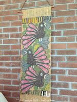 Textile wall hanging with colorful birds on a brick wall