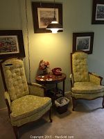 Full view of telephone corner with two matching upholstered chairs, round wooden phone table with vintage rotary phone, small flower bouquet, and hanging white pendant lamp.
