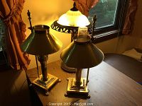 Three lamps shown on wooden table near a window, including two matching brass lamps and a larger stained glass lamp.