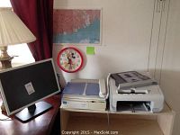 Dell computer monitor, Canon copy machine, and Canon fax machine on wooden desk, all visible during photo. Items arranged side by side next to lamp and wall clock.