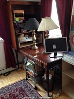 Desk with hutch, showing top compartments and surface including two brass lamps and monitor on top.