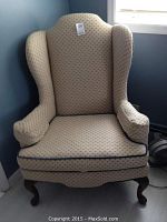 Front view of one wingback chair showing full silhouette, upholstery pattern and wood legs.