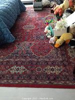 Full view of the oriental rug on floor with toys placed on one side showing the overall pattern and condition