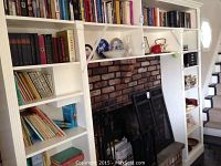Bookshelves filled with various hardcover books including classic literature, mysteries, and boating books alongside fireplace
