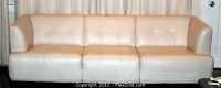 Front view of the white leather 3-cushion couch showing tufted cushions and slightly discolored seat.