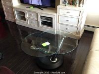 View of the glass table in a living room, showing the round glass top and metal supports.