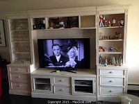 Full assembled wall unit with mounted flat-screen TV, two side towers and central console.