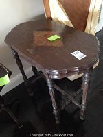 Full view of the decorative wooden table showing carved legs and scalloped top edge with diamond inlay.