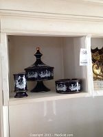Display shelf showing three blue etched Florentine decorative pieces with white etched classical figures and gold trim, lit evenly for clear viewing.