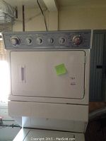 Front view of Maytag stacked washer and dryer unit with a sticky note on the dryer door.